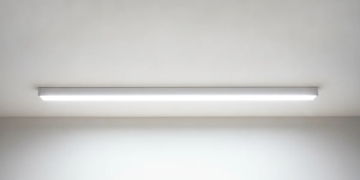 Längliche weiße Leuchte, die unter einer weißen Decke leuchtet